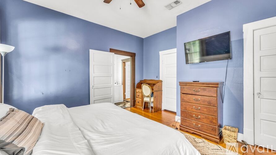 A bedroom with blue walls and a white bed.