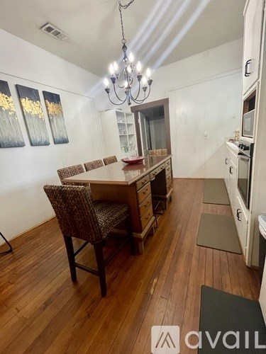 A kitchen with a wooden table and chairs and a chandelier.