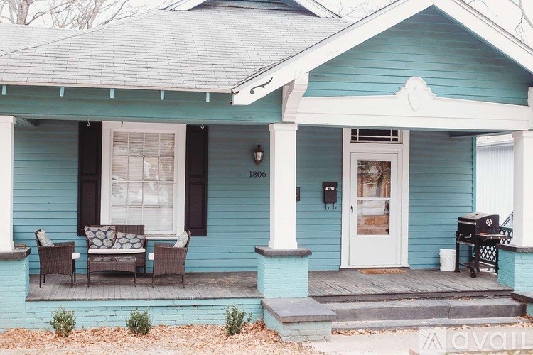A blue house with a white door and a porch with a couch and chairs.