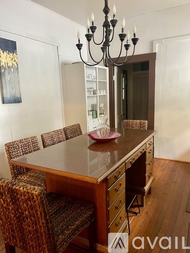 A brown wooden dining table with four chairs and a chandelier.