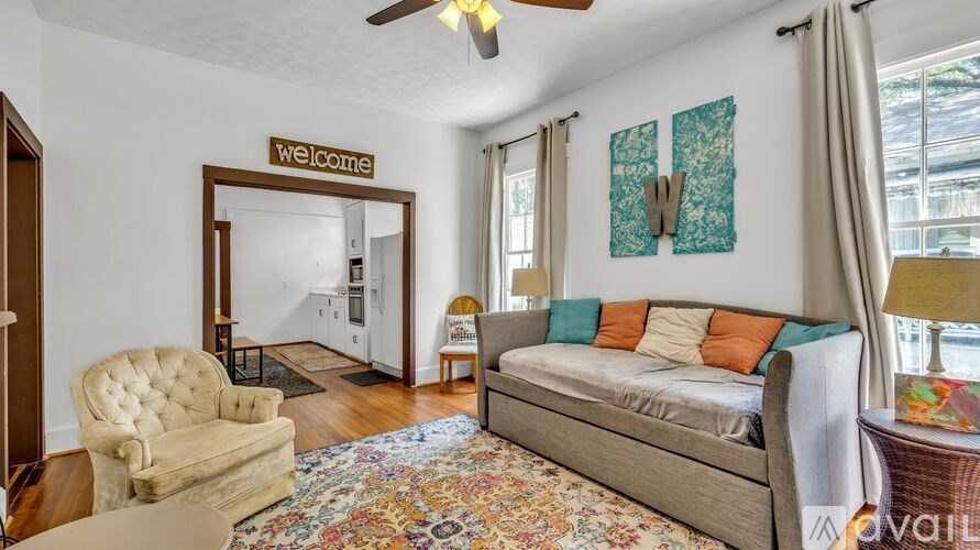 A living room with a beige sofa, a chair, and a rug.
