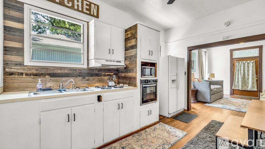 A kitchen with white cabinets and a window with a view of trees.