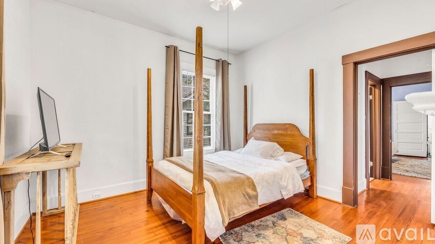 A bedroom with a four poster bed and a television on a stand.
