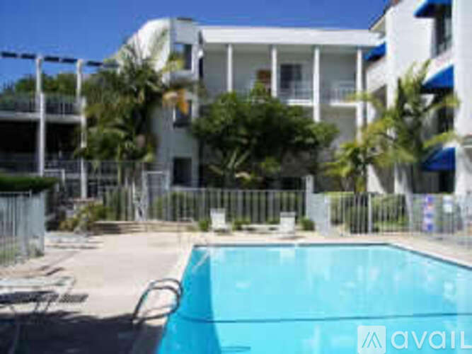 A pool in front of a white building with a balcony.