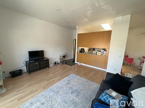 A living room with a black couch and a television.