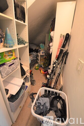 A small, messy room with a laundry basket on the floor.