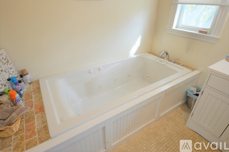A bathroom with a tub, sink, and window.
