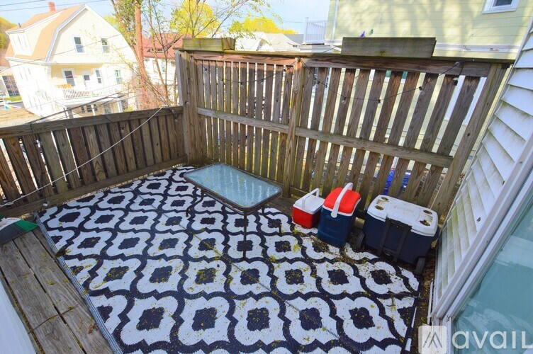 A wooden deck with a black and white patterned rug and two coolers on it.