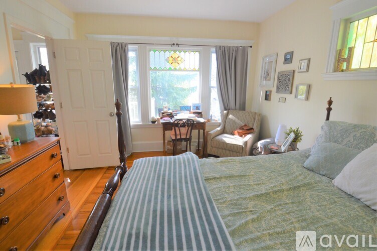 A bedroom with a bed, chair, and window.