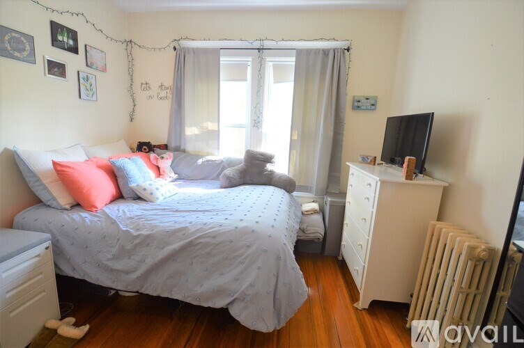 A bedroom with a bed, a dresser, and a window.