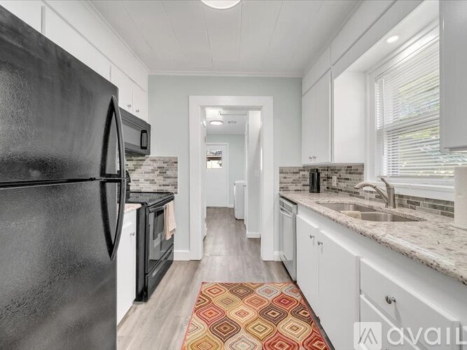 A kitchen with black appliances and white cabinets.