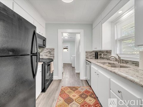 A kitchen with black appliances and white cabinets.