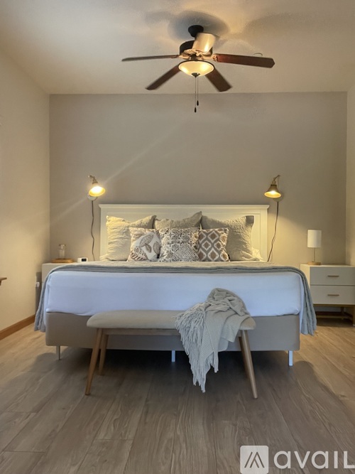 A bedroom with a bed, nightstand, and a ceiling fan.