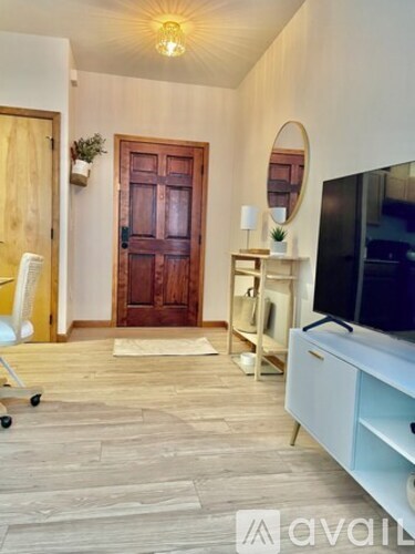 A living room with a wooden door, a flat screen TV, and a wooden floor.