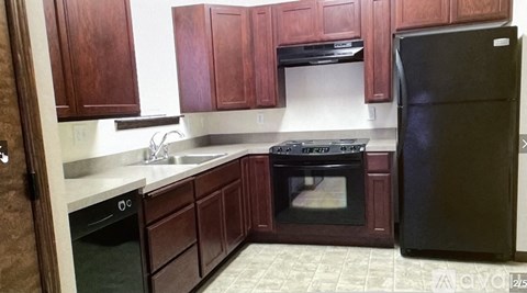 A kitchen with wooden cabinets and a black refrigerator.