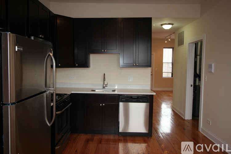 A kitchen with black cabinets and a stainless steel refrigerator.