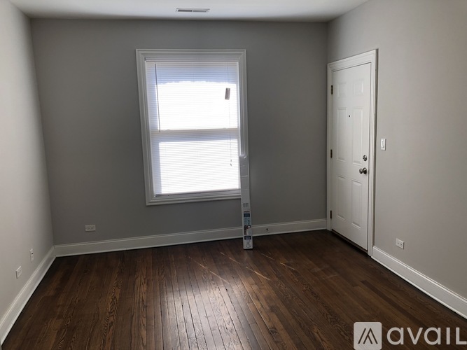 A room with wooden floors and a window with blinds.