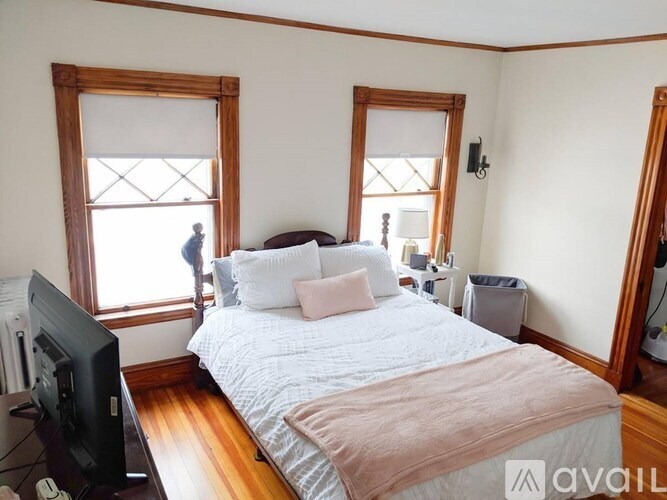 A bedroom with a bed, a television, and a window.