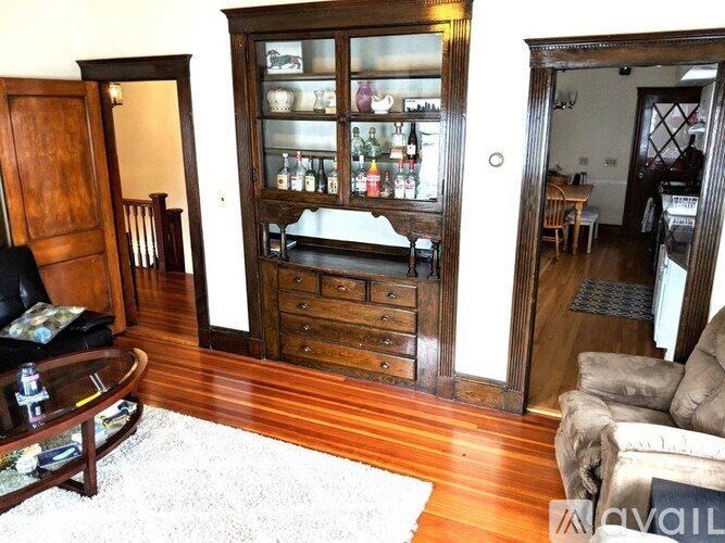 A living room with a wooden floor and a glass door cabinet.