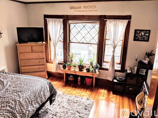 A bedroom with a bed, dresser, and window.