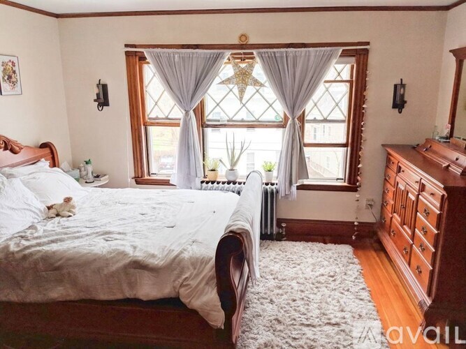 A bedroom with a large bed and a window with curtains.