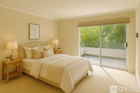 A bedroom with a large bed and a view of trees through the sliding glass door.