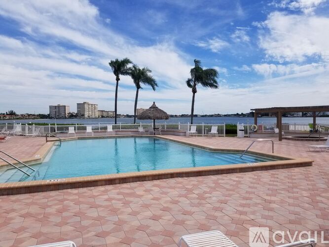 A pool surrounded by palm trees and a tiki hut.