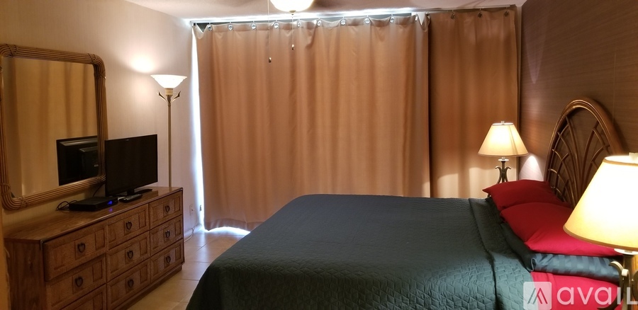 A bedroom with a bed, a dresser with a mirror, and a lamp.