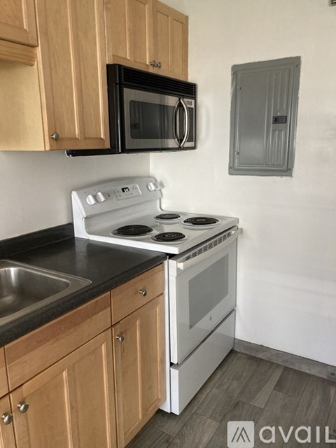 A kitchen with wooden cabinets and a white stove top oven.