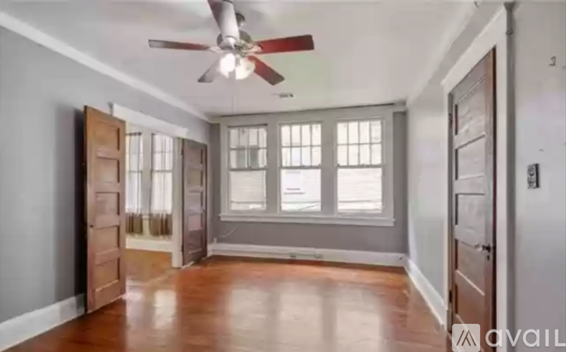 A room with a ceiling fan and wooden floors.