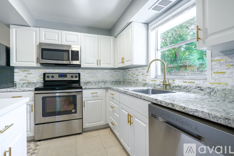 A kitchen with white cabinets and a marble countertop.