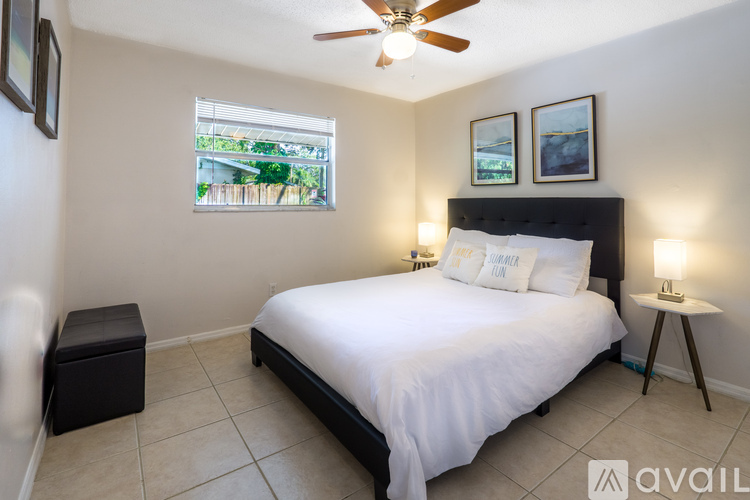 A bedroom with a large bed, a window with a view, and a ceiling fan.