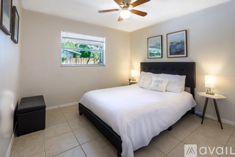A bedroom with a large bed, a window with a view, and a ceiling fan.