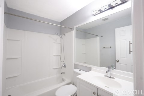 A white bathroom with a toilet, sink, and bathtub.