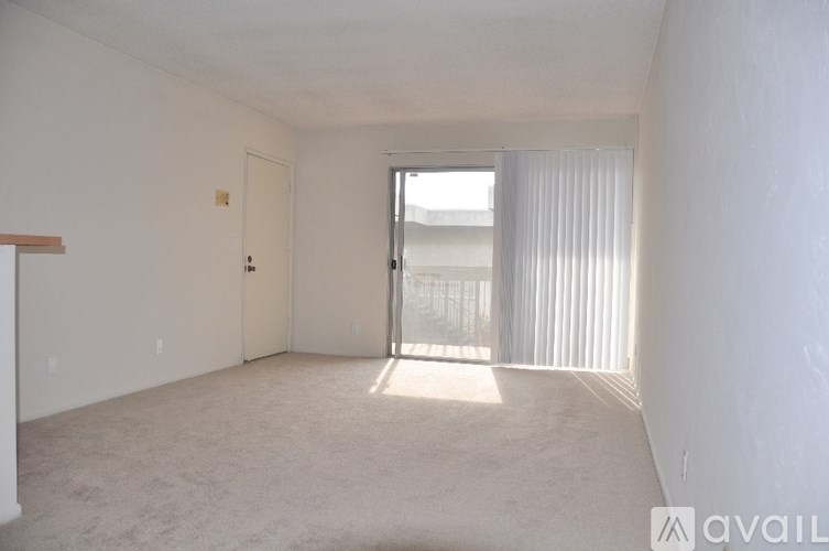 A room with a carpeted floor and a sliding glass door leading to a balcony.