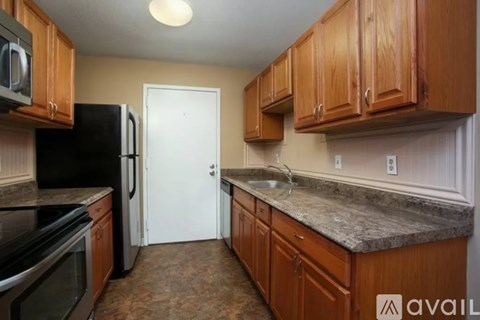 A kitchen with wooden cabinets and a black refrigerator.