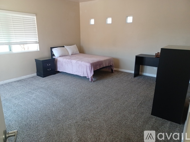 A bedroom with a bed, nightstand, and desk.
