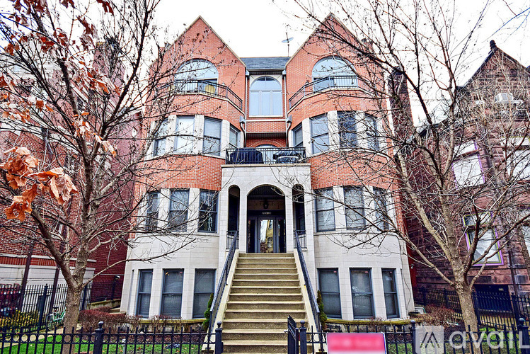 A large red brick building with a black fence and a staircase leading to the entrance.