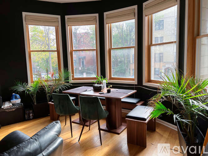 A room with a table and chairs in front of three windows.