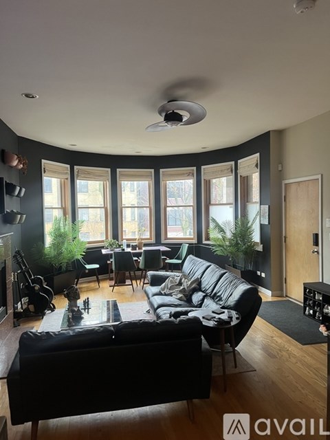 A living room with a black couch and a fan on the ceiling.