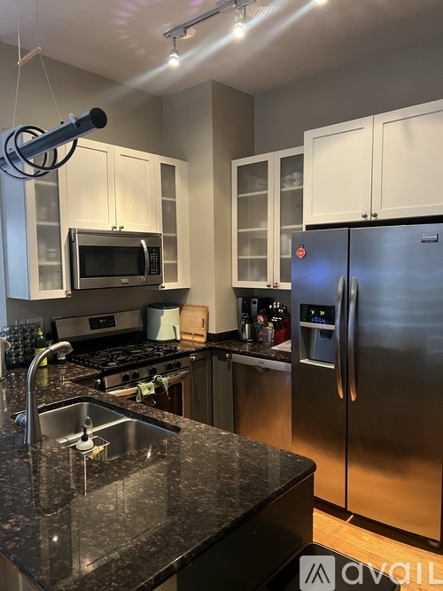 A kitchen with a black granite counter top and stainless steel appliances.