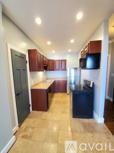 A kitchen with brown cabinets and a black fridge.