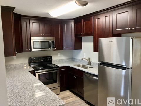 A kitchen with dark wood cabinets and stainless steel appliances.
