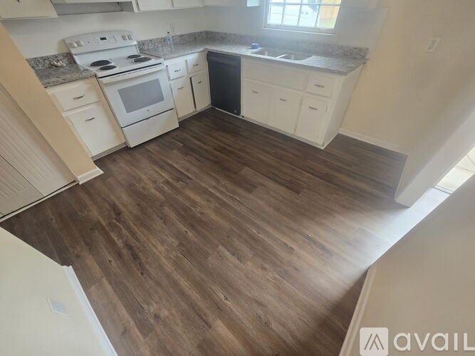 A kitchen with white appliances and wooden floors.