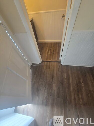 A hallway with wood flooring and white walls.