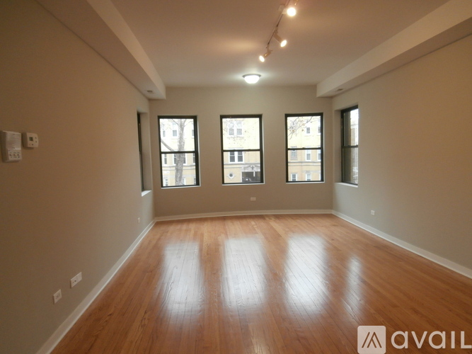Empty room with wooden floors and three windows.