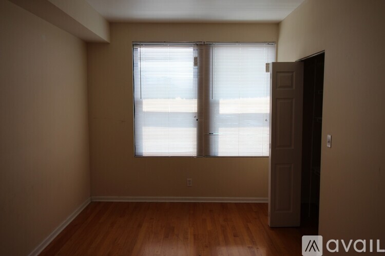 A room with wooden floors and a window with blinds.