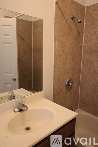 A bathroom with a sink, mirror, and shower.
