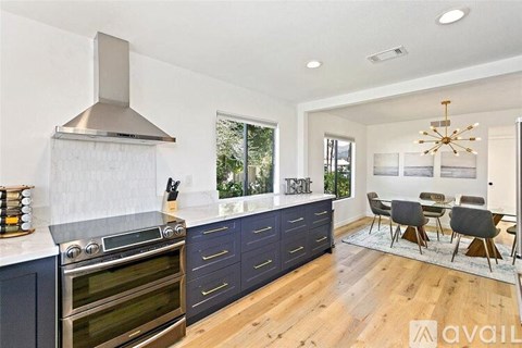 A modern kitchen with dark blue cabinets and a stainless steel range hood.