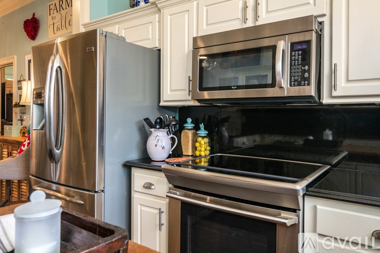 A kitchen with a stainless steel refrigerator and microwave above a stove.